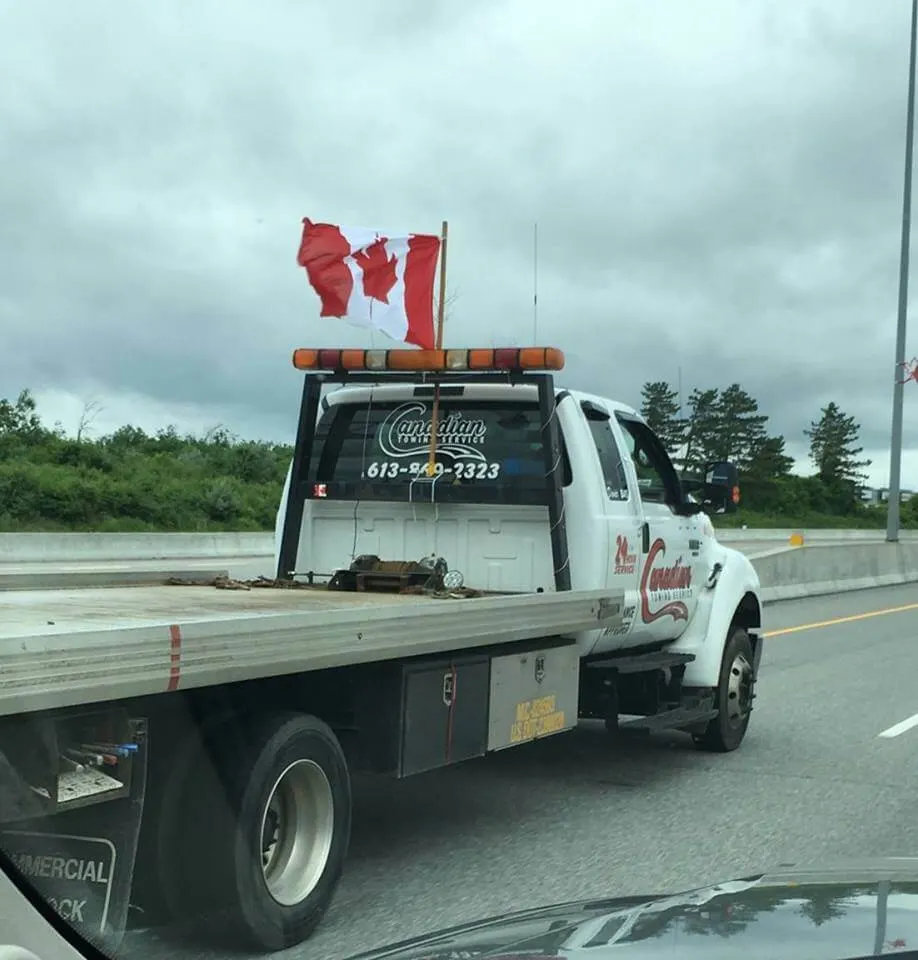 Canadian Towing flatbed with Canadian flags on the highway